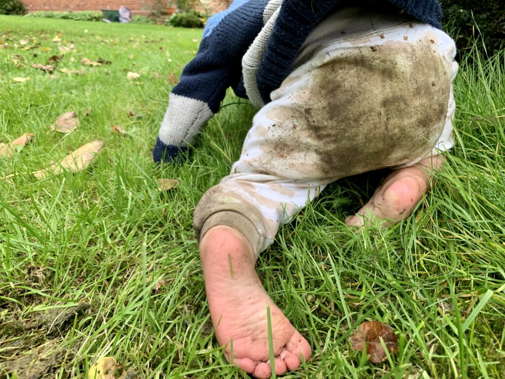 Kind krabbelt im Gras mit dreckiger Hose