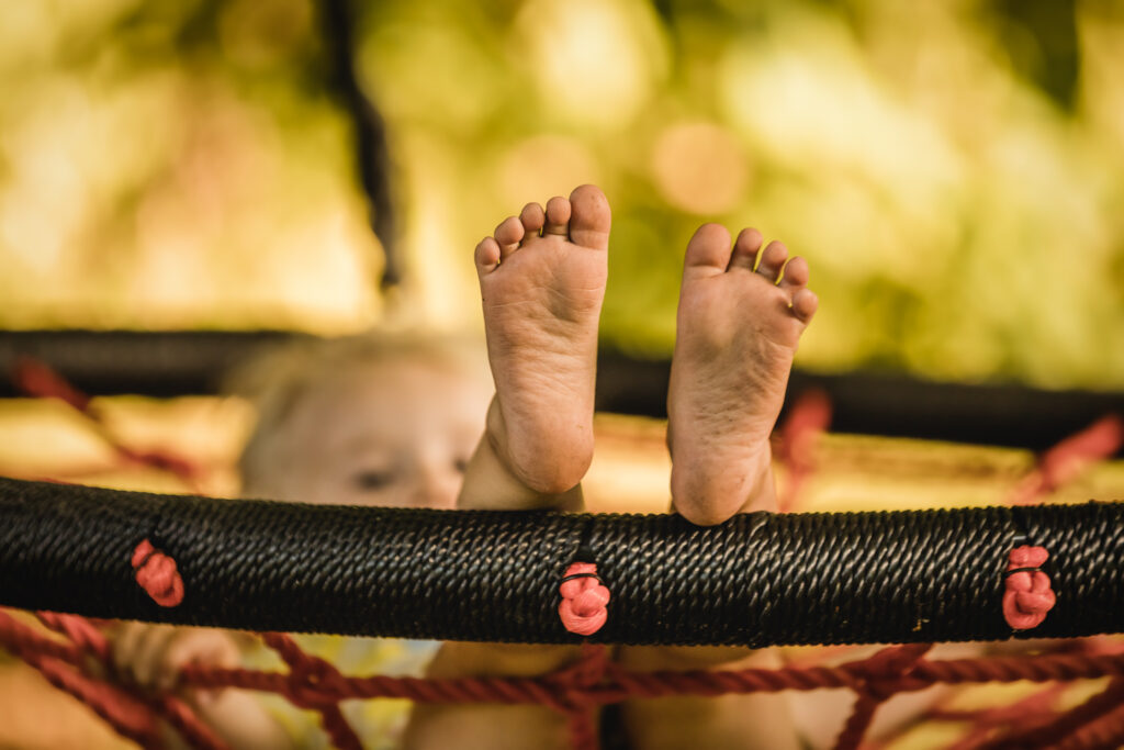 Kinderfüße ohne Socken auf Schaukel