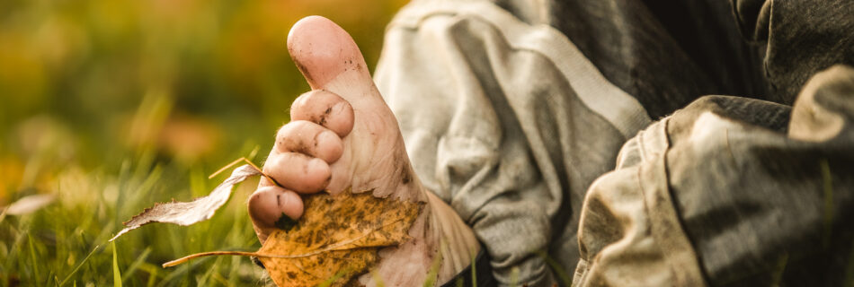 Kind barfuß auf einer Wiese im Herbst