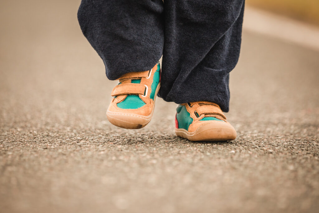 Kind läuft mit Barfußschuhen draußen