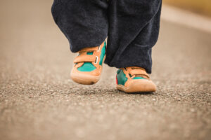 Kind läuft mit Barfußschuhen draußen